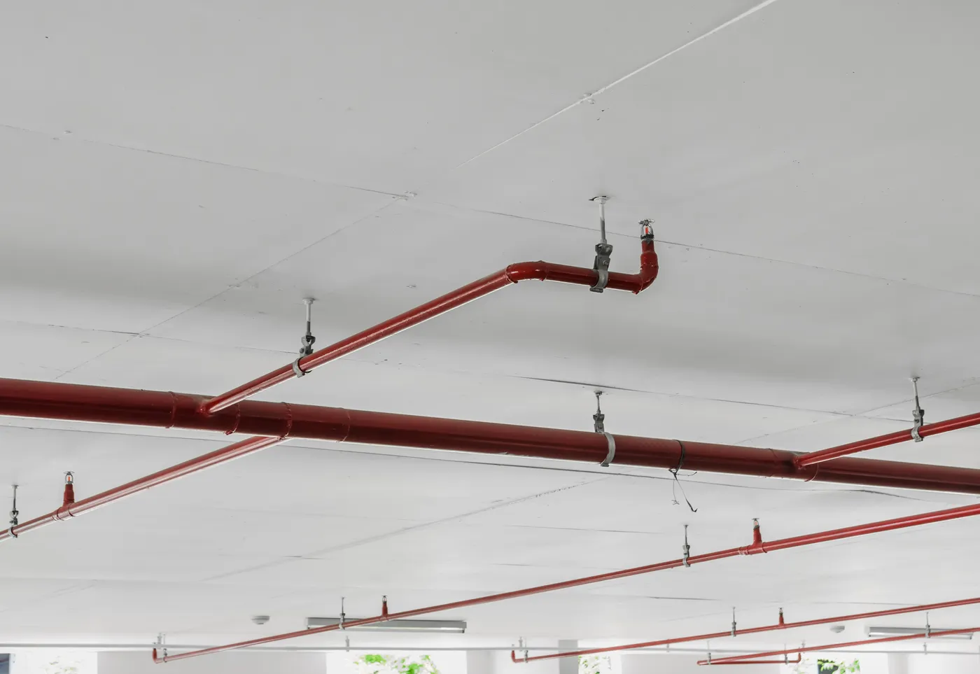 Red automatic fire sprinkler piping and pendent heads on a concrete ceiling