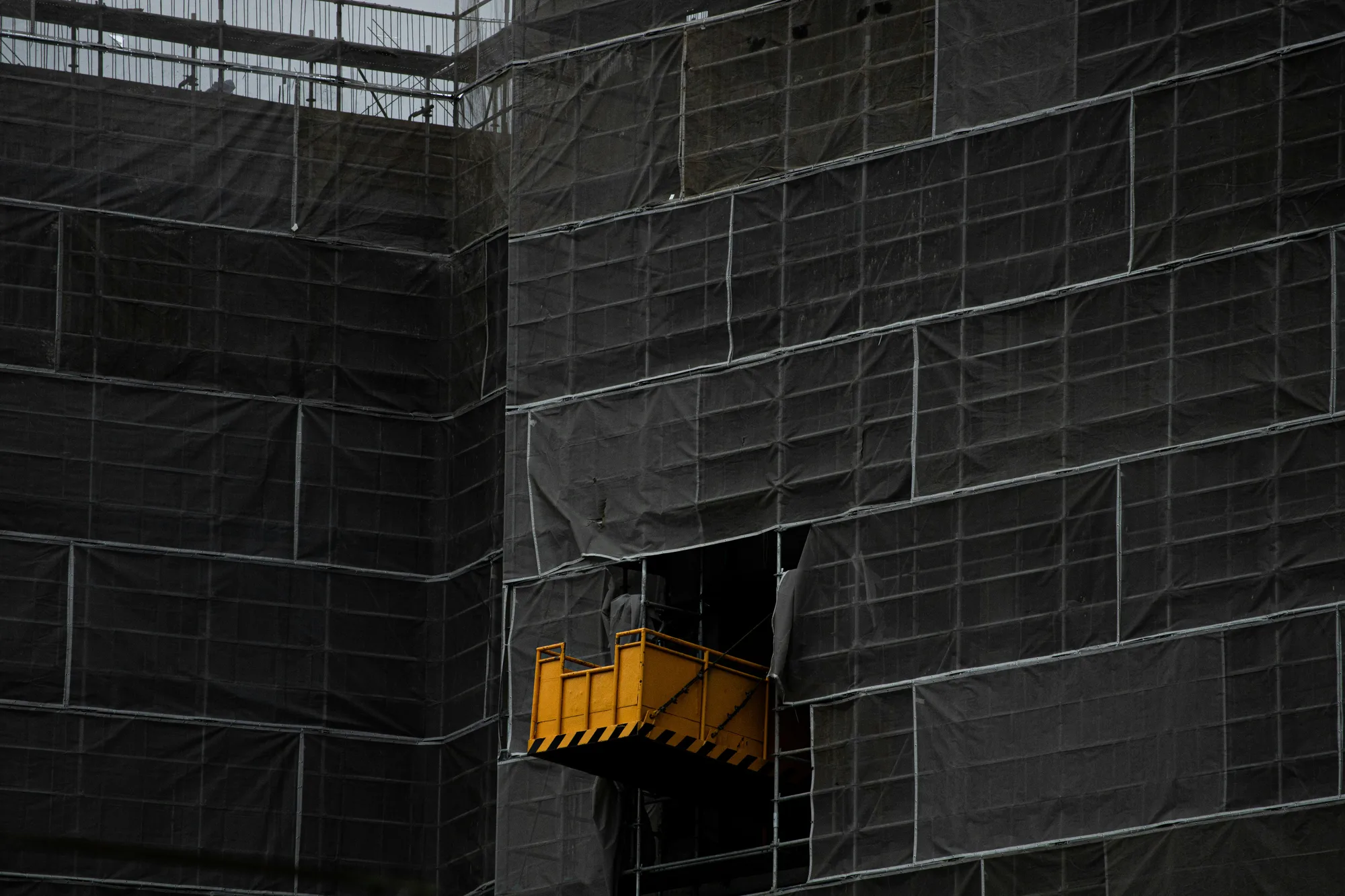 Commercial building under construction wrapped in protective scaffolding netting