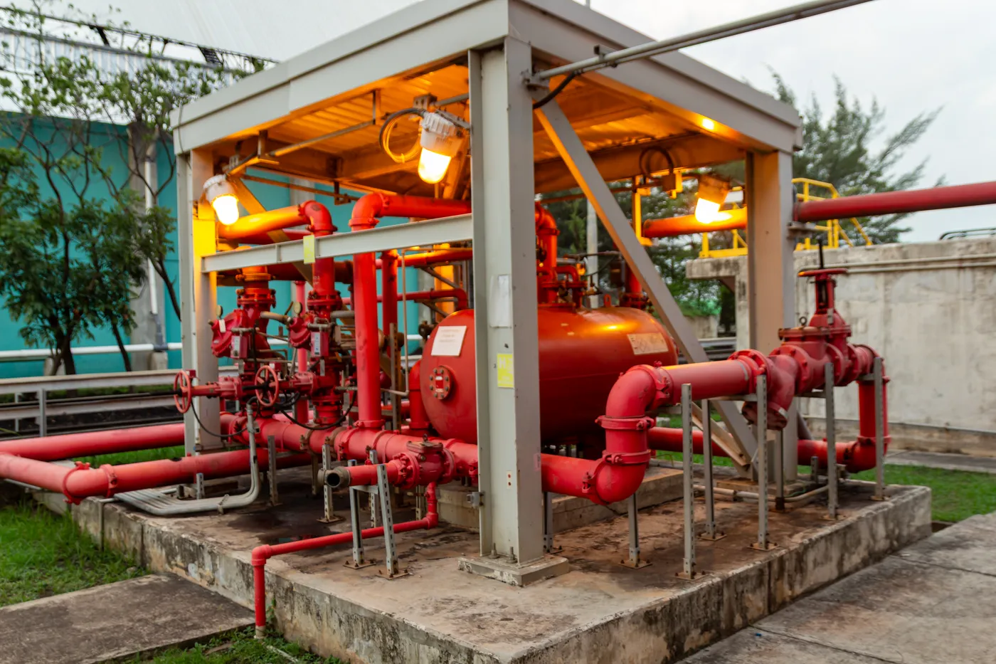 Outdoor foam fire suppression skid with a red bladder tank and piping