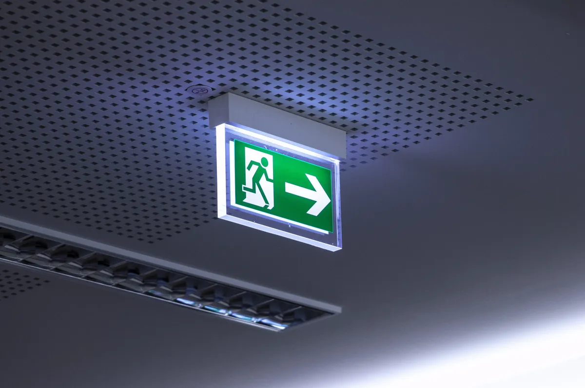 Illuminated emergency exit sign on a ceiling marking an egress route